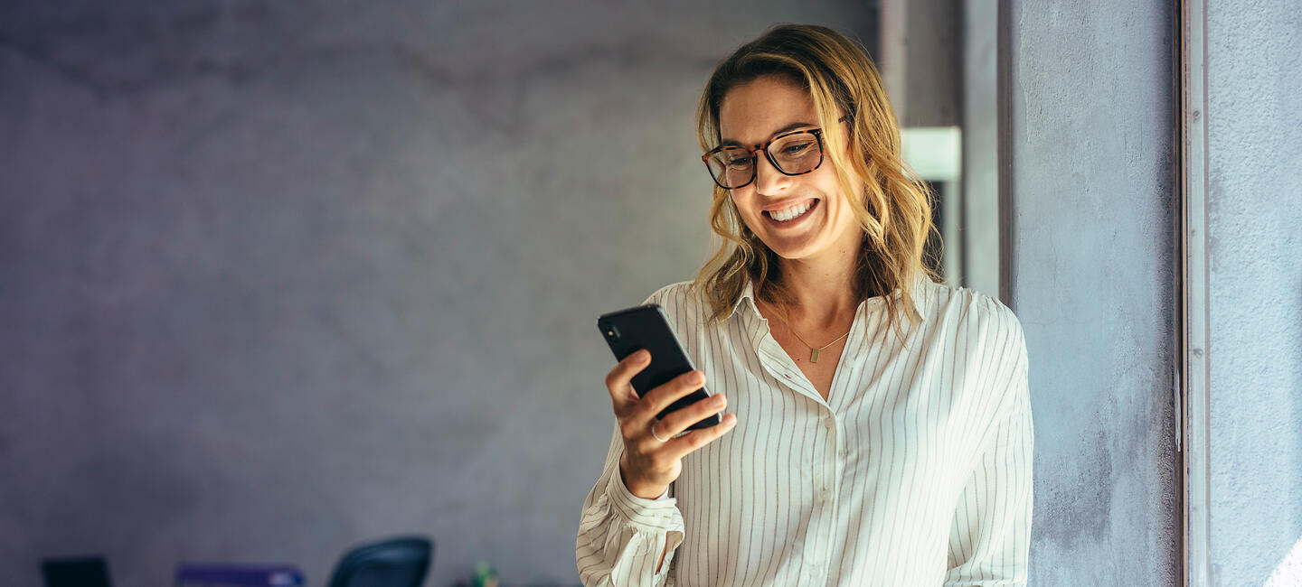 Frau berechnet an ihrem Handy die Kosten für eine Berufsunfähigkeitsversicherung